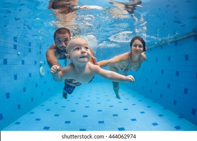 Happy full family - mother, father, baby son learn to swim, dive underwater with fun in pool to keep fit. Healthy lifestyle, active parent, people water sport activity, swimming lesson. Focus on child