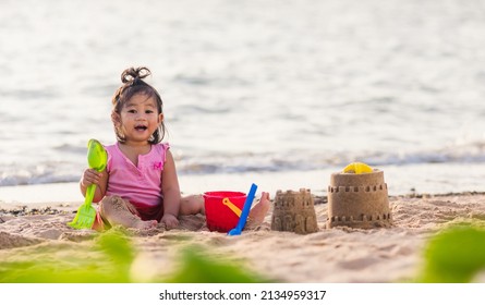 Happy fun Asian child cute little girl playing sand with toy sand tools at a tropical sea beach in holiday summer on sunset time, tourist trip concept - Powered by Shutterstock