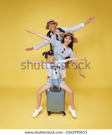 Happy fun asian family vacation portrait. Father, mother and two daughters ready for travel flight with suitcase isolated on yellow studio background.