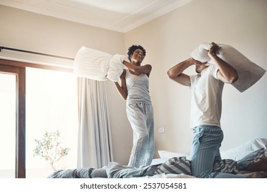 Happy, fun and playful pillow fight of a loving couple playing in their bedroom at home. Funny male and female laughing, smiling and fighting with pillows in pajamas on the bed in the morning. - Powered by Shutterstock