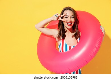 Happy fun young sexy woman slim body wear striped red blue one-piece swimsuit hold pink inflatable ring isolated on vivid yellow color wall background studio Summer hotel pool sea rest sun tan concept