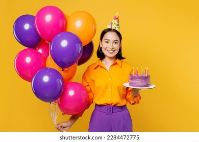 Happy fun young woman wears casual clothes hat celebrating hold bunch of colorful air balloons cake with candles look camera isolated on plain yellow background. Birthday 8 14 holiday party concept - Powered by Shutterstock