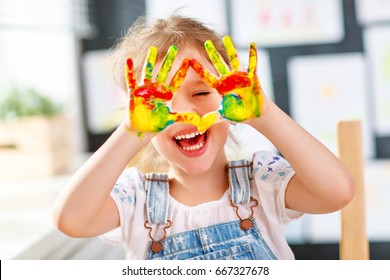 happy funny child girl draws laughing shows hands dirty with paint
 - Powered by Shutterstock