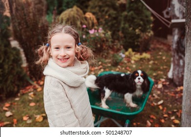 Happy Funny Child Girl Riding Her Dog In Wheelbarrow In Autumn Garden, Candid Outdoor Capture, Kids Playing With Pets