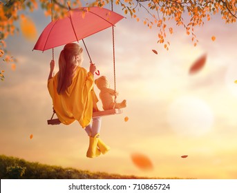 Happy Funny Child With Red Umbrella. Girl Is Wearing Yellow Raincoat And Rubber Boots. Kid Playing On The Nature Outdoors. Family Walk In The Park.