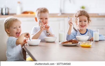 happy funny children sister and brothers eating breakfast