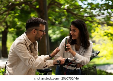 Happy funny couple with bicycle in the park. Loving couple enjoying together outdoors.	