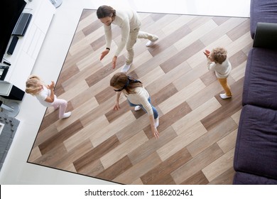 Happy Funny Family With Little Preschool Son And Daughter Spending Free Time Together On Weekend At New Modern Home. Playful Mom With Covered Eyes Playing Hide And Seek In Living Room, Top Above View.