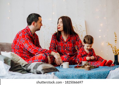 Happy Funny Family With Their Son In The Bedroom In The Same Beautiful Christmas Pajamas.