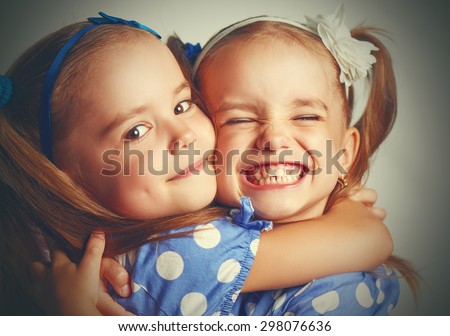 Happy funny girl twins sisters hugging and laughing