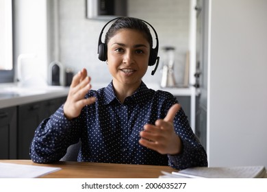 Happy Funny Indian Student Wearing Headphones And Microphone Looking At Webcam, Smiling At Camera, Laughing During Virtual Meeting Or Video Call Talk. Employee Working From Home. Screen View Head Shot