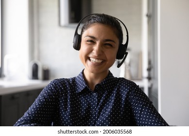 Happy Funny Indian Student Wearing Headphones And Microphone Looking At Webcam, Smiling At Camera, Laughing During Virtual Meeting Or Video Call Talk. Employee Working From Home. Screen View Head Shot