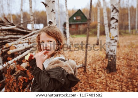 Foto Bild fröhlich lustiges Kind Mädchen isst frischen Apfel im Herbst