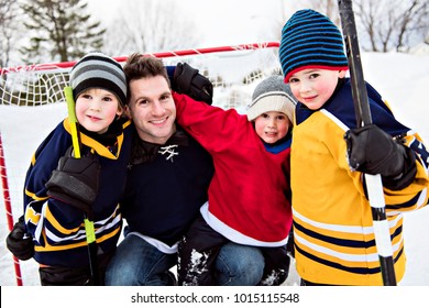 Happy Funny Kids Playing Hockey With Father On Street In The Winter Season