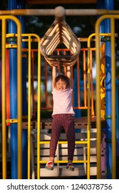 Happy Funny Little Asian Girl Playing Alone With Monkey Bar At The Playground. Image Of Emotional Cheerful Adorable Kid Having Fun In Summer Of Outdoors. Education Activity For Kid Concept.