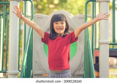 Happy Funny Little Girl Playing Merry Go Around At The Playground Outdoor In The Daytime Summer. Outdoor Activity. Playing Make Believe And Outside Education Concept.