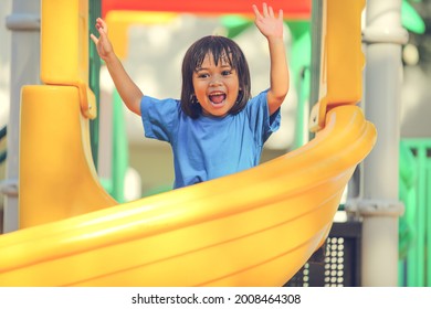 Happy Funny Little Girl Playing Merry Go Around At The Playground Outdoor In The Daytime Summer. Outdoor Activity. Playing Make Believe And Outside Education Concept.