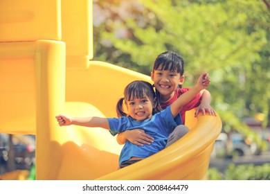 Happy Funny Little Girl Playing Merry Go Around At The Playground Outdoor In The Daytime Summer. Outdoor Activity. Playing Make Believe And Outside Education Concept.