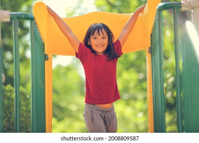 Happy Funny Little Girl Playing Merry Go Around At The Playground Outdoor In The Daytime Summer. Outdoor Activity. Playing Make Believe And Outside Education Concept.