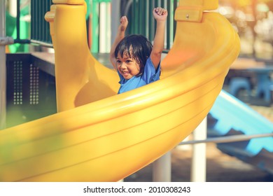 Happy Funny Little Girl Playing Merry Go Around At The Playground Outdoor In The Daytime Summer. Outdoor Activity. Playing Make Believe And Outside Education Concept.