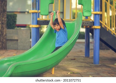 Happy Funny Little Girl Playing Merry Go Around At The Playground Outdoor In The Daytime Summer. Outdoor Activity. Playing Make Believe And Outside Education Concept.