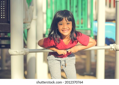 Happy Funny Little Girl Playing Merry Go Around At The Playground Outdoor In The Daytime Summer. Outdoor Activity. Playing Make Believe And Outside Education Concept.