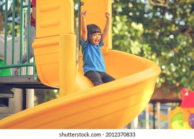 Happy Funny Little Girl Playing Merry Go Around At The Playground Outdoor In The Daytime Summer. Outdoor Activity. Playing Make Believe And Outside Education Concept.