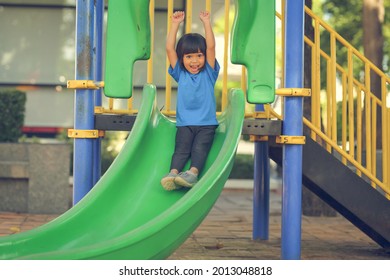 Happy Funny Little Girl Playing Merry Go Around At The Playground Outdoor In The Daytime Summer. Outdoor Activity. Playing Make Believe And Outside Education Concept.