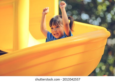 Happy Funny Little Girl Playing Merry Go Around At The Playground Outdoor In The Daytime Summer. Outdoor Activity. Playing Make Believe And Outside Education Concept.