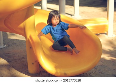 Happy Funny Little Girl Playing Merry Go Around At The Playground Outdoor In The Daytime Summer. Outdoor Activity. Playing Make Believe And Outside Education Concept.