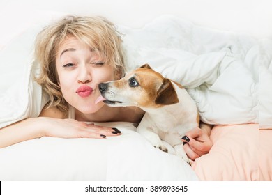 Happy Funny Morning Mood. Fooling Around With Pet On Bed. Relaxed Sleepy Woman And Dog Kiss On The Pillow And Linen 