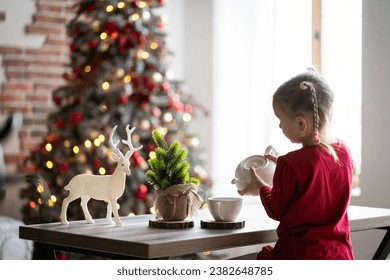 happy funny small girl in christmas pijama preparing tea, christmas morning in the kitchen. Christmas family harmony. Christmas child in the kitchen. - Powered by Shutterstock