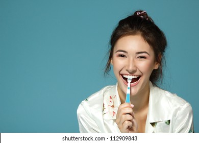 Happy funny teen girl brush her teeth. Morning theme. Over blue background.