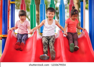 Happy funny three little children playing with slide at the playground.Image of emotional cheerful adorable asian kids have fun in the outdoors. education activity for kid concept.