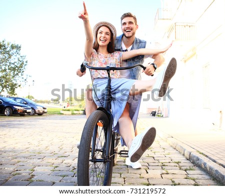 Happy funny young couple riding on bicycle. Love, relationship, romance concept.