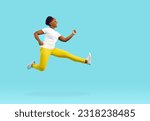 Happy funny young dark skinned woman having fun running and jumping on light blue background. Full length woman in white t-shirt, yellow pants and sunglasses fooling around near copy space.