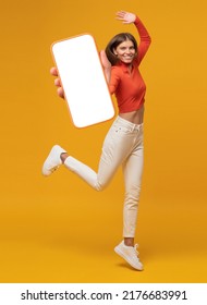 Happy Funny Young Woman Jumping And Showing Blank Phone Screen With Copy Space For App, Isolated On Yellow Background