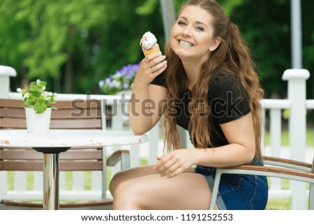 Happy funny young woman with long brown hair eating ice cream having fun.