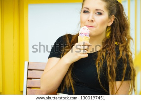 Happy funny young woman with long brown hair eating ice cream having fun.