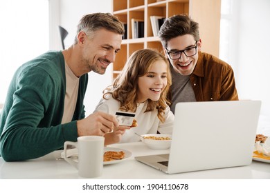 Happy Gay Couple And Adopted Child With Laptop At Home, Shopping With Credit Card