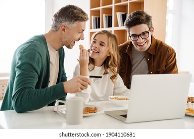 Happy Gay Couple And Adopted Child With Laptop At Home, Shopping With Credit Card