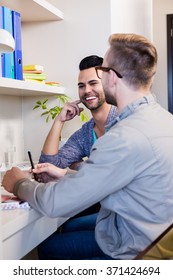 Happy Gay Couple Discussing In Office