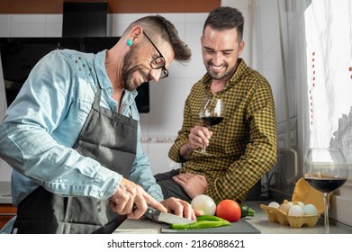 Happy Gay Couple In Love Standing In The Kitchen. They Are Cooking Dinner Together At Home. High Quality Photography