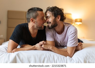 Happy Gay Couple Lying Down On The Bed At Home, Hugging And Flirting. LGBT Gay Couple Love Moments Happiness Concept