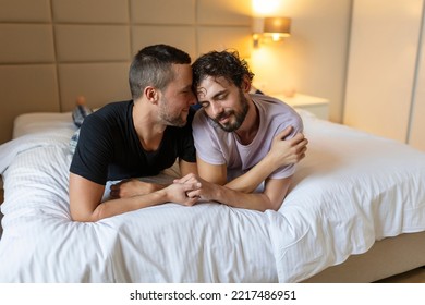 Happy Gay Couple Lying Down On The Bed At Home, Hugging And Flirting. LGBT Gay Couple Love Moments Happiness Concept