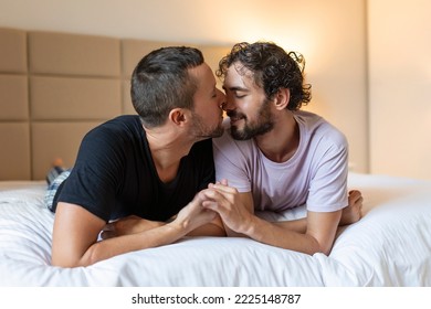 Happy Gay Couple Lying Down On The Bed At Home, Hugging And Flirting. LGBT Gay Couple Love Moments Happiness Concept