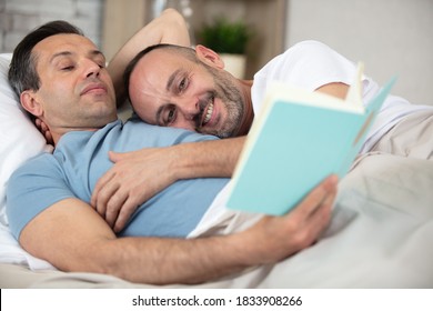 Happy Gay Couple Reading Book On Bed