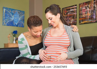 Happy gay female couple looking at womb