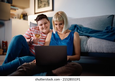 Happy Gay Woman And Her Girlfriend Using Laptop While Relaxing In The Living Room.