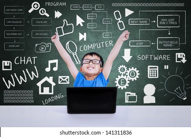 Happy geek boy winning computer science competition using laptop in class